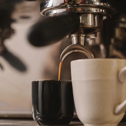 Dos tazas bajo el portafiltro recibiendo el espresso