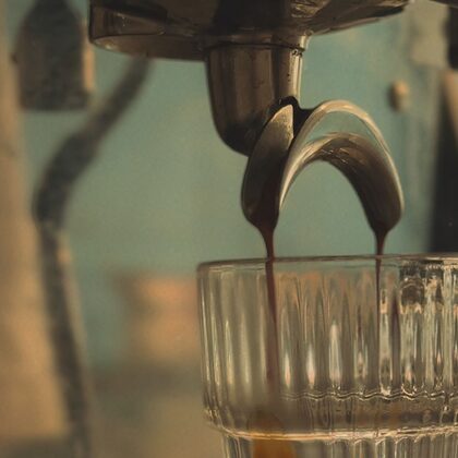 Espresso cayendo del portafiltro a un vaso de cristal labrado