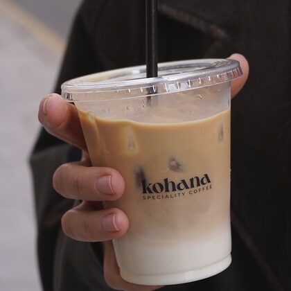 Vaso de latte con el logotipo de Kohana en la mano
