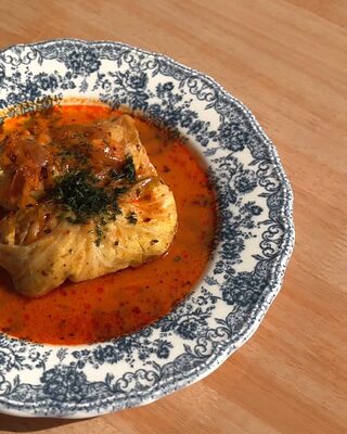 Rollito de col en salsa de tomate con eneldo, en un plato de loza azul