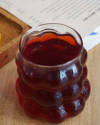 Té rojo en un vaso de cristal ondulado sobre la mesa de madera