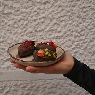 Una mano sostiene un plato con dulces de chocolate y fruta