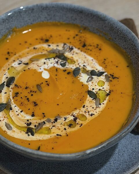 Sopa de calabaza en cuenco azul con crema, semillas de calabaza y aceite