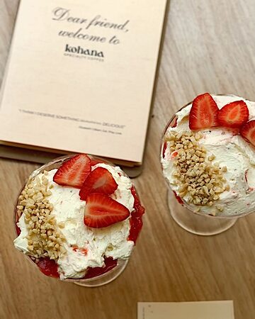 La tarjeta «Dear friend, welcome to Kohana» junto a dos copas de fresas con nata